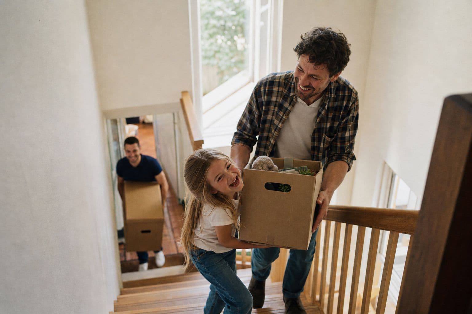 Father and daughter carrying a moving box up the stairs together